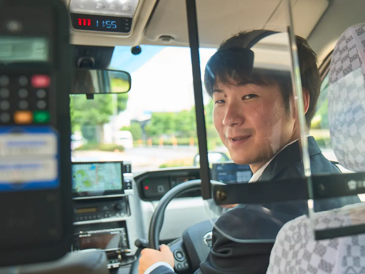 タクシー車内で後席のお客様へ笑顔を向ける乗務員